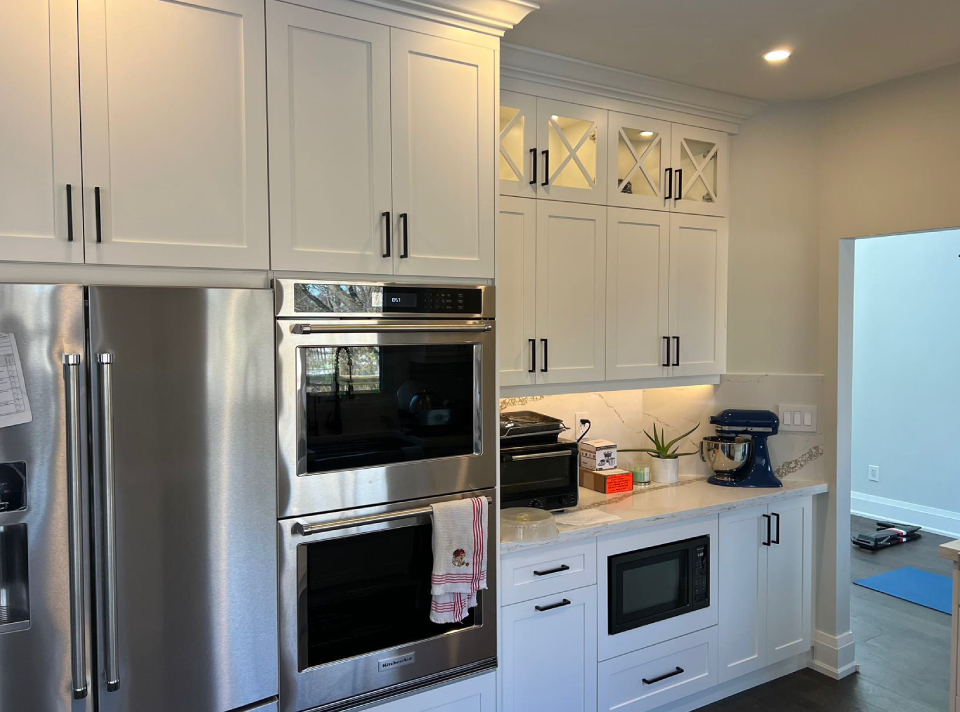 White custom Shaker kitchen cabinets with matte black hardware and built-in stainless steel appliances installed in an Oakville home by Envyland Kitchen Cabinet.